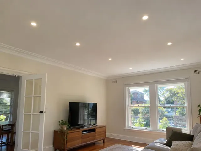 Living room ceiling with recessed downlights, white cornice and windows in a cream home in Beecroft