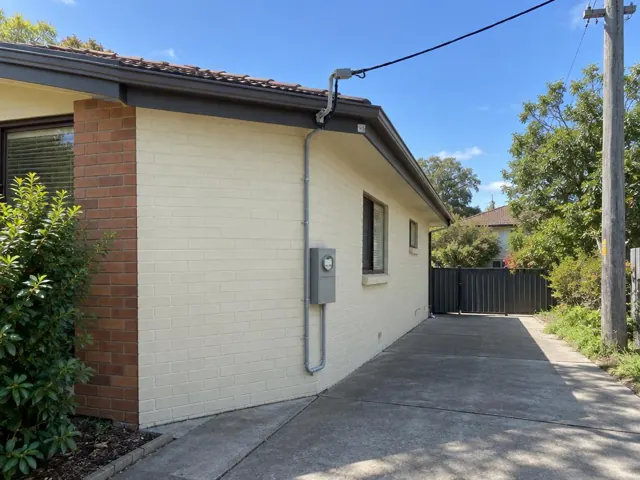 Overhead service cable and point-of-attachment bracket on a brick house exterior in Carlingford